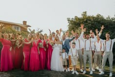 a group of people standing next to each other in front of a house with their hands up