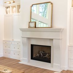 a living room with a fire place in the middle and white furniture on the other side