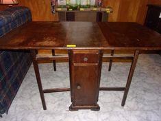 an old wooden desk in the corner of a living room with a couch and lamp