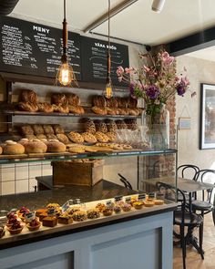 a bakery filled with lots of pastries sitting on top of a counter next to a table