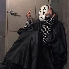 a person wearing a mask sitting in front of a locker with their hands up to the door