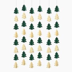 christmas tree ornaments hanging from strings on a white background with green and gold trees in the middle