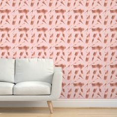 a white couch sitting in front of a wall with pink and orange designs on it