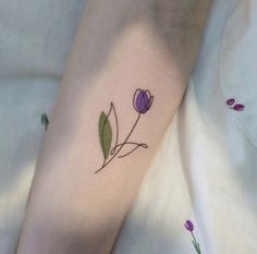 a small flower tattoo on the left arm and leg, with purple flowers around it