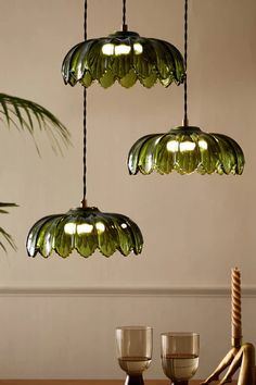 three green glass lights hanging over a wooden table