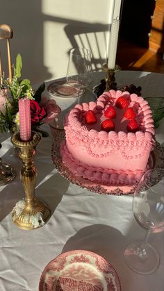 a heart shaped cake sitting on top of a table next to wine glasses and candles