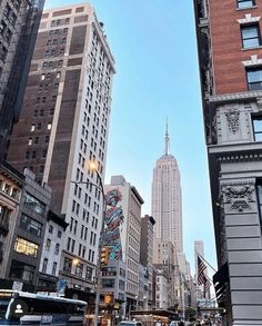 a city street with tall buildings and cars driving down it's sides in front of the empire building