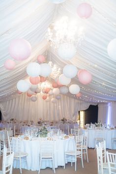 a room filled with lots of tables covered in white and pink balloons