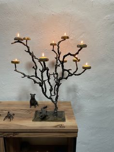 a small tree with candles in it sitting on a wooden table next to a white wall