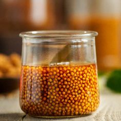 a glass jar filled with mustard sitting on top of a table