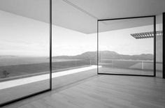 an empty room with large glass walls overlooking the ocean and mountain range in black and white