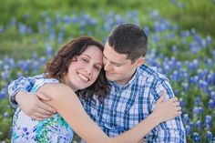 a young man and woman hugging in a field of bluebonallions with their arms around each other