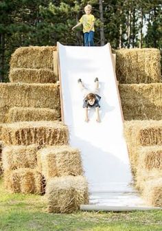 a young boy sliding down a slide made out of hay bales