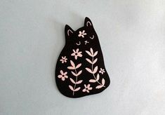 a black cat brooch with pink flowers on it