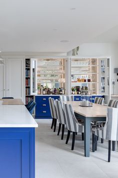 a kitchen with blue cabinets and white countertops has striped chairs around a table in the center