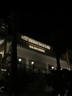 the entrance to swanton house hotel lit up at night with palm trees in front