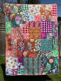 a colorful quilt hanging on the side of a fence