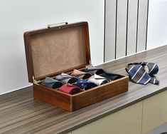 an open suit case sitting on top of a wooden counter next to a tie box