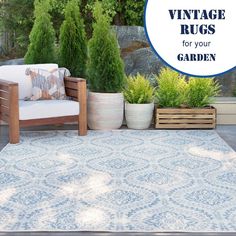 a blue and white rug sitting on top of a wooden floor next to potted plants