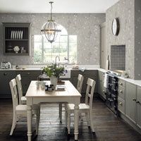 a white table and chairs in a room with wooden flooring, cabinets and windows