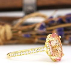 an orange and white diamond ring sitting on top of a table next to purple flowers