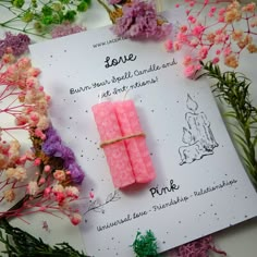 two pink candles are tied to a card surrounded by flowers