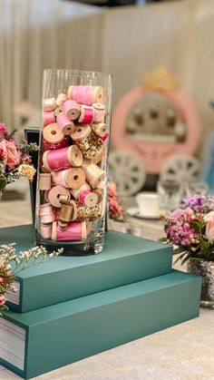 two vases filled with pink flowers and wooden spools