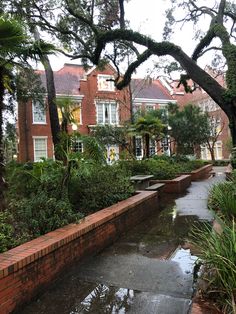 an outdoor garden with brick walls and water running through the center, surrounded by trees