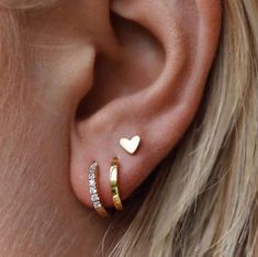 a woman's ear with two gold hearts on it