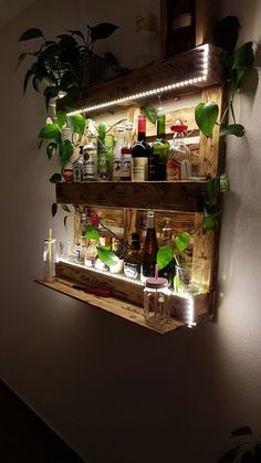 a wooden shelf filled with bottles and plants next to a wall mounted planter on the side of a wall