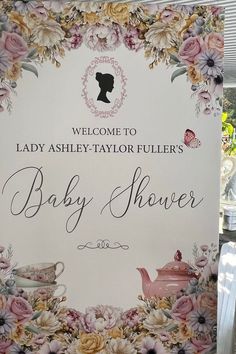 a welcome sign for a baby shower with flowers and teapots in the background