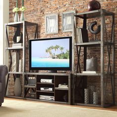 a living room with a large television and brick wall in the backround area