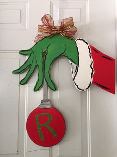 a door hanger with a hand holding a red ornament and a ribbon on it