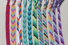 several different colored braided bracelets hanging on a wall