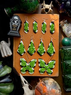 a table topped with lots of green and white earrings on top of a wooden board