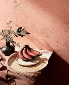 a plate with some bananas on it next to a potted plant and a vase