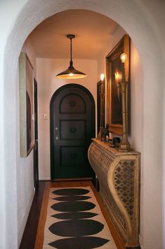 an archway leading to a hallway with a black door and white rug on the floor