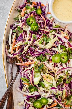 a white plate topped with coleslaw next to a bowl of dressing