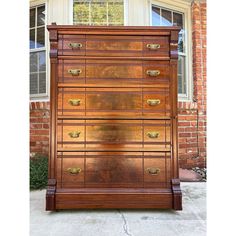 a large wooden chest of drawers in front of a brick building with windows on each side