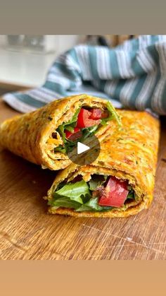 a burrito cut in half sitting on top of a wooden cutting board