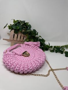 a pink handbag sitting on top of a white table next to a green plant