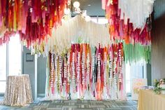 the room is decorated with colorful streamers hanging from the ceiling and tables in front of it