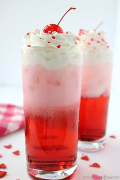 two red drinks with whipped cream and a cherries garnish on the top