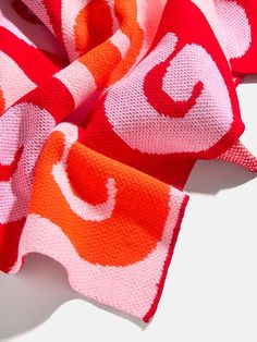 an orange and pink scarf laying on top of a white surface with the letter c in red