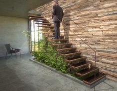 a man standing on top of a set of stairs next to a planter filled with plants