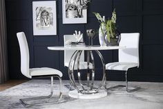 a white table and chairs in a room with pictures on the wall behind it,