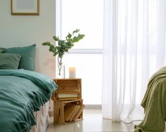 a bed with green sheets and pillows next to a window