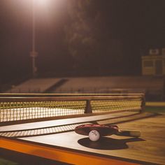 two ping pong paddles resting on the edge of a tennis court at night