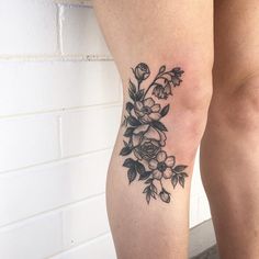 a woman's leg with a flower tattoo on her left side, next to a brick wall