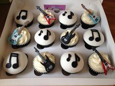 cupcakes decorated with musical instruments and music notes are displayed in a white box